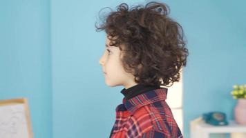 The bored boy looks out the window. The bored child at home is looking out the window. Quarantine, playing in the playground. video