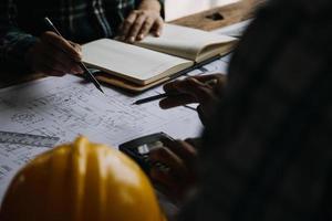 construcción y estructura concepto de ingeniero trabajando dibujo en Plano reunión para proyecto trabajando con compañero en modelo edificio y Ingenieria herramientas en trabajando sitio, construcción concepto foto