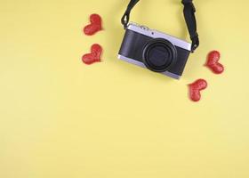 plano laico de digital cámara con rojo Brillantina corazones en amarillo antecedentes con Copiar espacio. foto