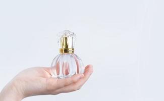 glass bottle with perfume in female hand isolated on white background photo