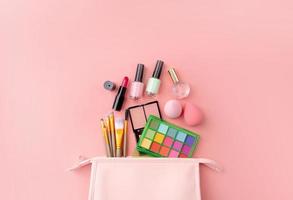 Bright summer eyeshadow palette and makeup products in pink cosmetic bag on pink background photo