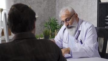 Senior mature doctor talking to his patient. Doctor man informing his patient about his illness. video
