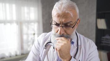 ouderen dokter is attent over patiënten en op zoek voor oplossingen. de attent senior dokter heeft veel problemen Aan zijn verstand. video