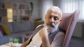 Senior man is thinking by playing with his beards. Mature man plays with his beard and is thoughtful. video