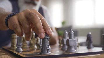 inteligente hombre jugando ajedrez solo. inteligente hombre jugando ajedrez solo a hogar hace y desarrolla estrategia. video