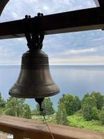 campana en el campanario de un cristiano Iglesia en contra el fondo de lago Baikal, Rusia foto