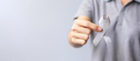 Brain Cancer Awareness month, woman hand holding grey color Ribbon for supporting people life. Healthcare and World cancer day concept photo