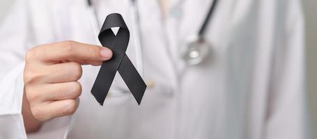 Melanoma and skin cancer, Vaccine injury awareness month and rest in peace concepts. doctor holding black Ribbon photo