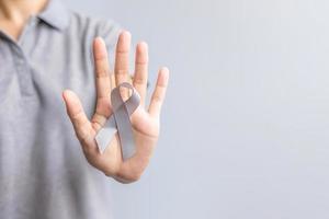 cerebro cáncer conciencia mes, mujer mano participación gris color cinta para secundario personas vida. cuidado de la salud y mundo cáncer día concepto foto