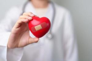 Doctor hand holding red heart shape in hospital. love, donor, world heart day, world health day, CSR donation and Insurance concepts photo