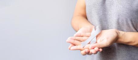 Brain Cancer Awareness month, woman hand holding grey color Ribbon for supporting people life. Healthcare and World cancer day concept photo