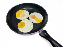 sunny side up eggs on a black pan isolated in white background photo