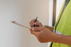 Building inspection, contractor asian young man, male inspecting home, reconstructed construction, renovation or check defect, before finish handing it over to client. Engineering worker, copy space. photo