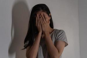 Mental health, depressed sad asian young woman, girl cover her face with hand, expression to face difficulty, failure and exhausted. Thoughtful worried suffering depression feeling lonely, alone. photo