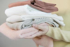 Feel softness, asian young woman, girl hand in holding pile, stack folding clean clothes after washing, laundry and dry. Household working at home. Laundry and maid, close up on white background.