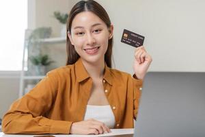 Convenience online internet banking, smile asian young woman hand in holding credit card to payment spending by scan qr code to transfer or pay money without cash. Technology of financial.