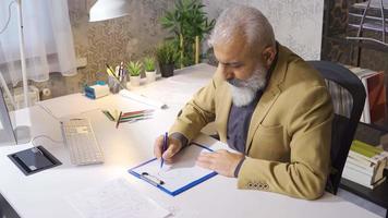 Mature businessman drawing and analyzing financial growth graph in his office. Businessman graphing financial expense statement. video