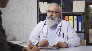 Senior mature doctor talking to his patient. Doctor man informing his patient about his illness. video