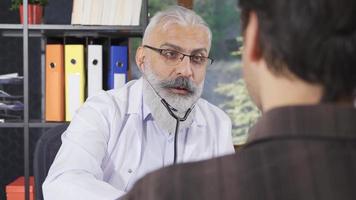 Senior doctor examining with stethoscope. Senior doctor examining his patient with a stethoscope. video