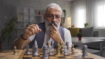 homem jogando xadrez sozinho às lar. pensativo homem jogando xadrez e pensando sobre dele movimentos. video