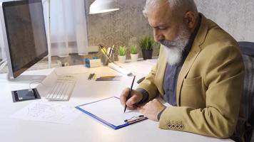 homme d'affaire dessin et en cours d'analyse graphique sur une pièce de papier. homme d'affaire en cours d'analyse moderne financier les dépenses et le revenu graphiques. video