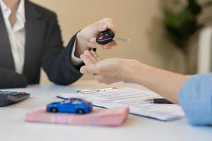 Business car rental company service, Close up hand of agent dealer giving, holding car key to customer renter, new owner after signed rental, purchase contract in document, vehicle sales agreement. photo