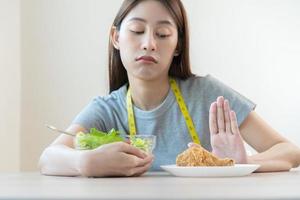 dieta, dieta asiático joven mujer o niña empujar afuera, negar frito pollo, basura comida y escoger Fresco vegetales ensalada de bol, comer comida para bueno saludable, salud cuando hambriento. hembra peso pérdida personas foto