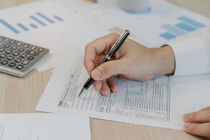 Close up hand of stress asian young employee business man, male calculate tax income and expenses, bills, credit card for payment or payday on table at home office. Financial, finance people concept. photo