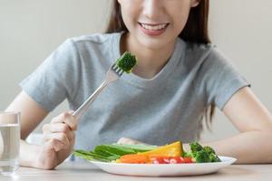 dieta, dieta asiático joven mujer o niña utilizar tenedor a brócoli en mezcla verduras, verde ensalada bol, comer comida es bajo grasa bueno salud. nutricionista femenino, peso pérdida para sano persona. foto