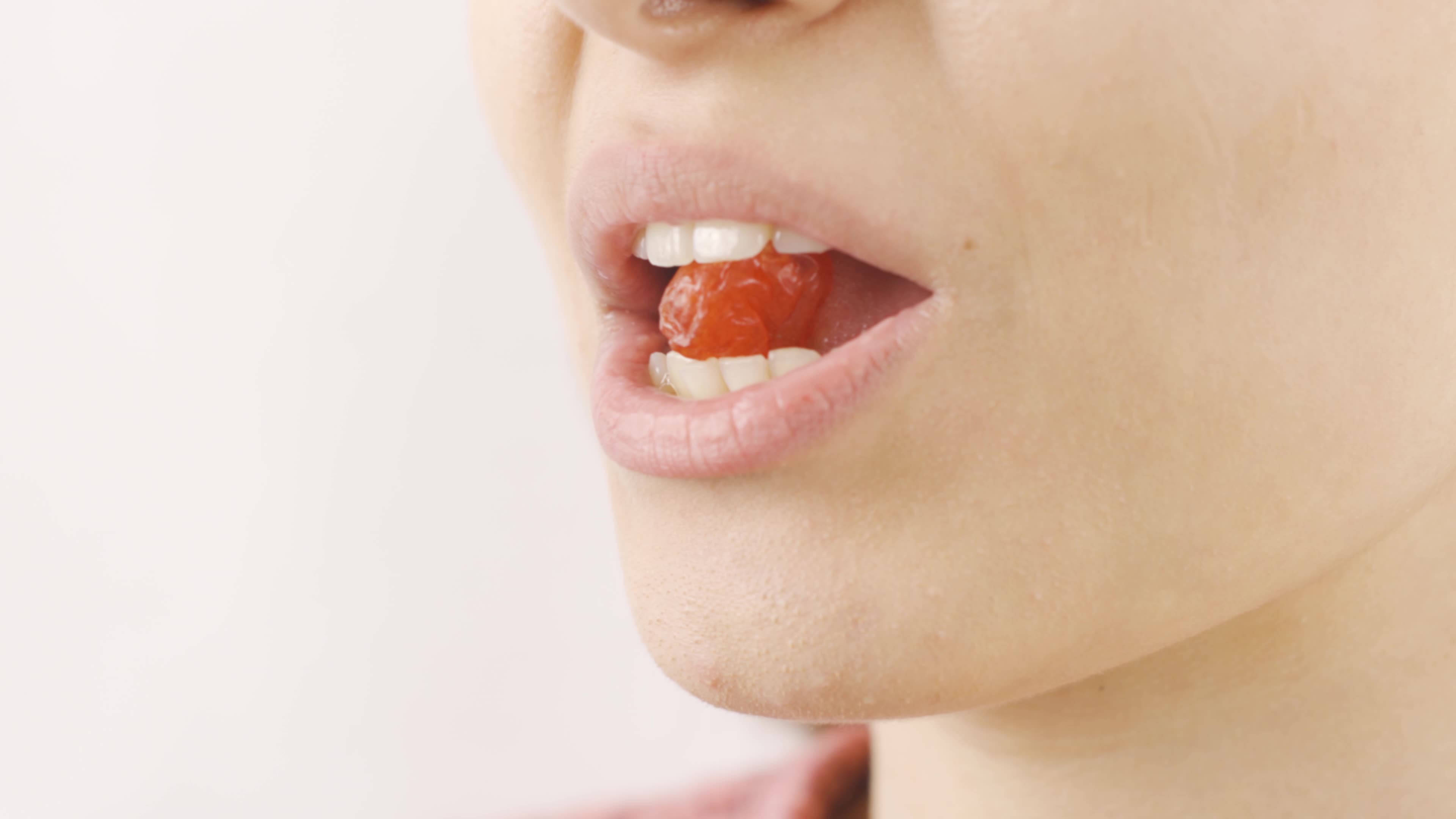 Woman eating dried cherries in closeup. Dry fruits. Closeup woman