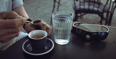 Elderly man drinking espresso coffee at an outdoor cafe photo