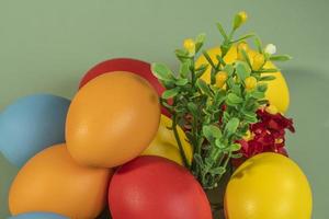 Colorful eggs, symbolizing Easter, on a colorful background and flowers photo