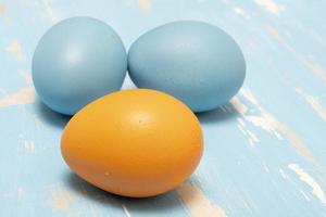 huevos simbolizando el Pascua de Resurrección fiesta en azul y naranja color en un antecedentes de Envejecido madera foto