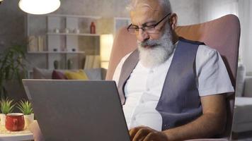 maturo uomo gioisce, sembra a il computer portatile e vince. maturo uomo guardare a il computer portatile a casa e gioia a che cosa lui vede. video