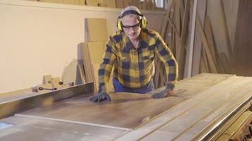 Carpenter man is cutting wood in workshop. The carpenter is cutting wood using a chainsaw. video