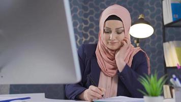 negocio mujer en hijab es pensando acerca de nuevo proyectos y nuevo ideas exitoso musulmán negocio mujer pensando para nuevo ideas en oficina y consiguiendo a trabajar. video