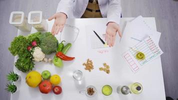 weiblich Ernährungsberater die Geschenke Lebensmittel zum gesund Leben. weiblich Ernährungsberater zum gesund Leben die Geschenke und zeigt an das Lebensmittel auf ihr Tisch. video