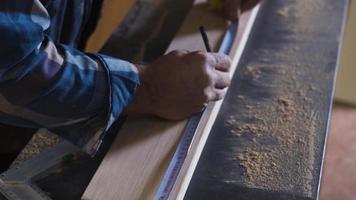 de cerca de madera medida. el carpintero es medición con el metro. de cerca, carpintero hombre medidas madera con metro en su polvoriento escritorio. video