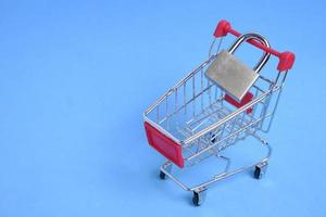 Shopping cart and padlock closed on it, business concept, budget reduction and minimalistic shopping. photo