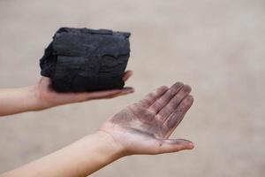 Closeup young boy's hand hold wooden charcoal and show his dirty hand with black stain of charcoal. Concept, learning to touch and observe  in science subject activity. Nature fuel photo