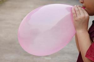 Closeup boy is blowing pink balloon, inflates  air to balloon Concept, children play, toy and equipment to play fun games or prepare party. photo