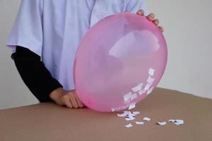 de cerca estudiante hacer Ciencias experimentar acerca de estático electricidad desde rosado globo y piezas de papel. concepto, Ciencias proyecto trabajo actividad. aprendizaje por haciendo. educación. foto