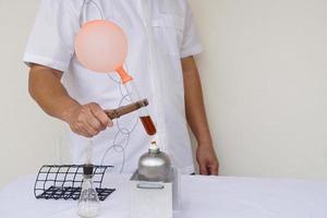 Closeup man is demostrating science exeriment about reaction of balloon on test tube is burned from lantern. The expanding of air pressure, reaction of chemical substance. Concept, Science activity. photo