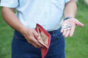 Closeup hand holds Thai baht coins and empty wallet. Concept, no money, economic crisis. Financial problems. Broke or less money at the end of month. photo