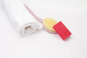 Rolled up towel with wash brush and pink soap on white isolated background. Cleanliness, care. Copy space