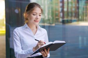 Successful business woman making notes in notebook outdoors in business photo