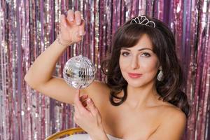 Woman in white dress with diadem on her head holds Christmas decorative mirror photo