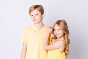 Two happy children standing near an empty gray background and hugging cute photo