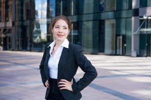 Business woman in suit uses smartphone. Big city with skyscrapers in background. Talking on the phone during the day photo