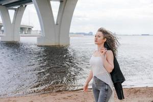 Young stylish woman in light light T-shirt and leather jacket and curly hair photo